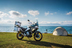 CFMOTO Mauritius 700MT motorcycle parked beside a tent near the water, ready for adventure.